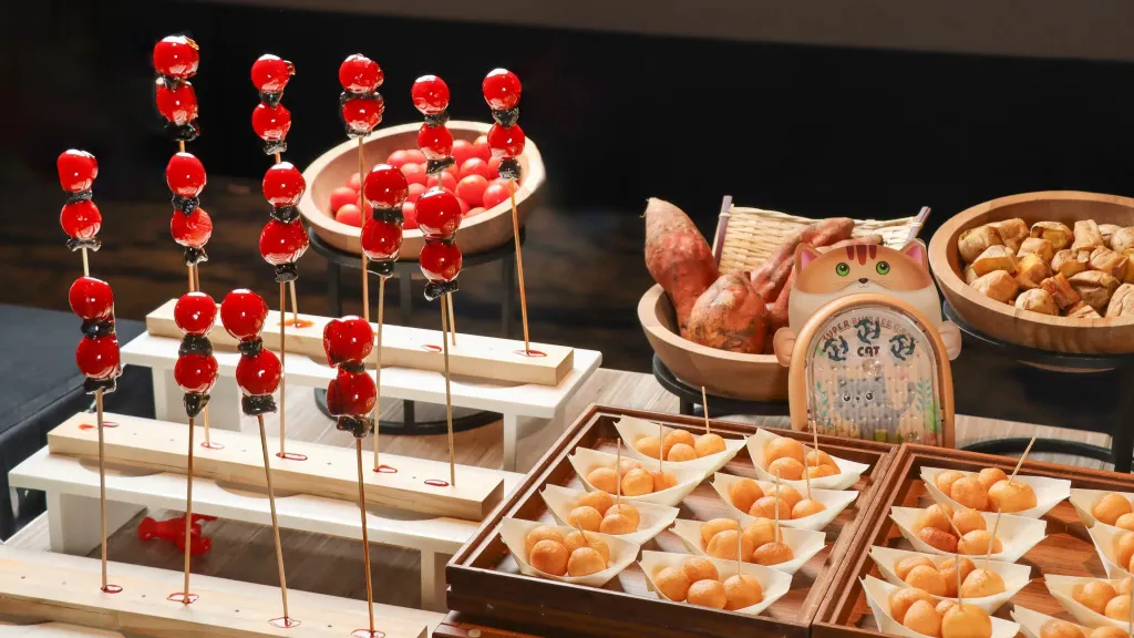 Présentation de brochettes de fruits rouges et de pâtisseries sur un buffet.