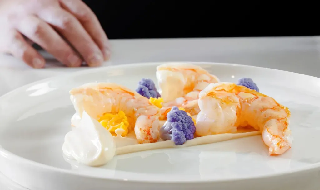 Assiette de crevettes et de chou-fleur décorée avec une sauce.