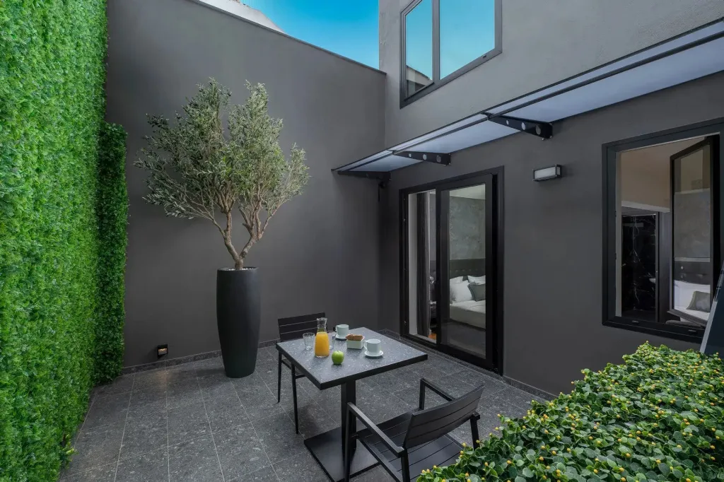 Une table et des chaises sont disposées sur une terrasse ombragée.