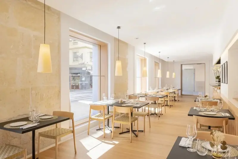Une salle lumineuse avec des tables dressées pour un repas.