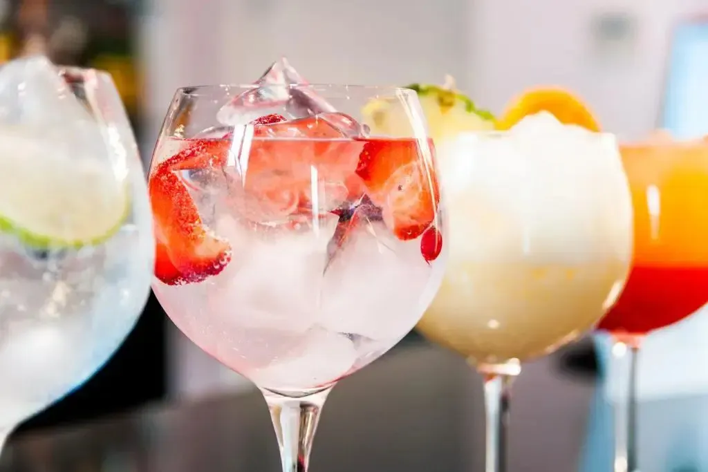 Des verres colorés garnis de fruits et de glace sont présentés au premier plan.