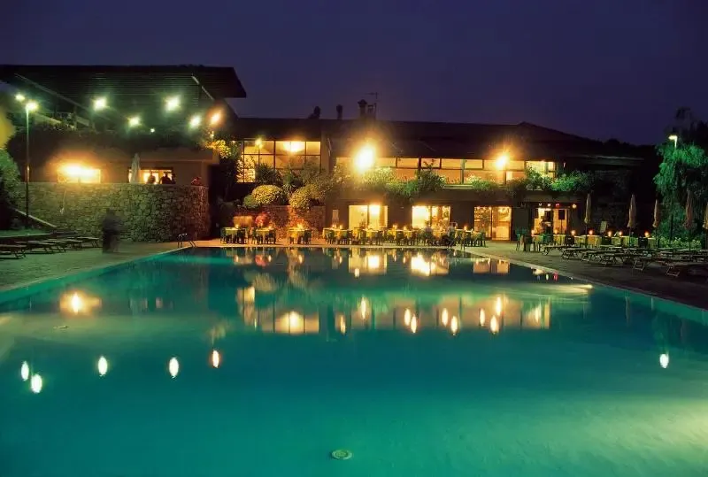 Piscine illuminée devant un bâtiment éclairé la nuit.