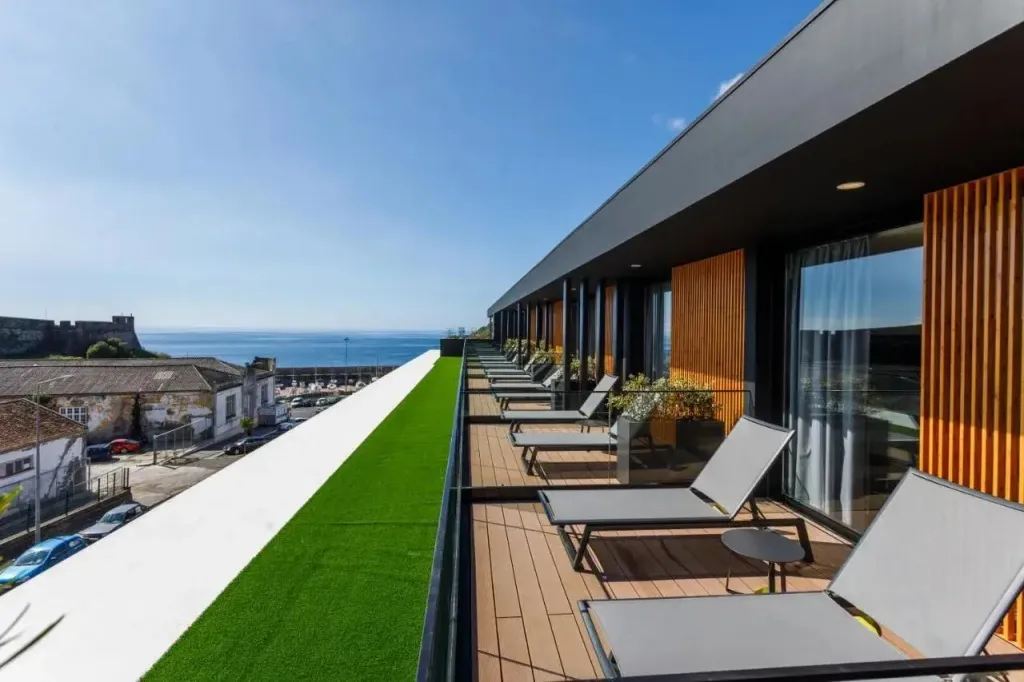 Terrasse avec transats et vue sur la mer et la ville.
