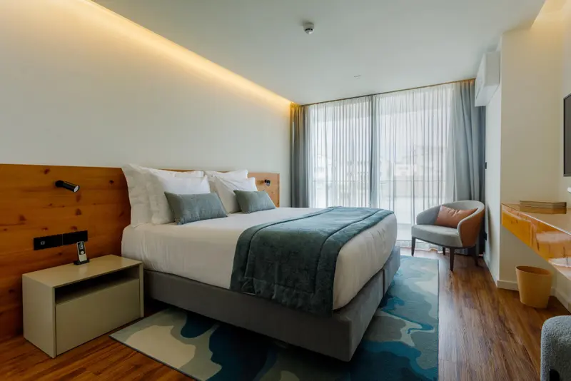 Une chambre lumineuse avec un grand lit et un fauteuil près d'une fenêtre.