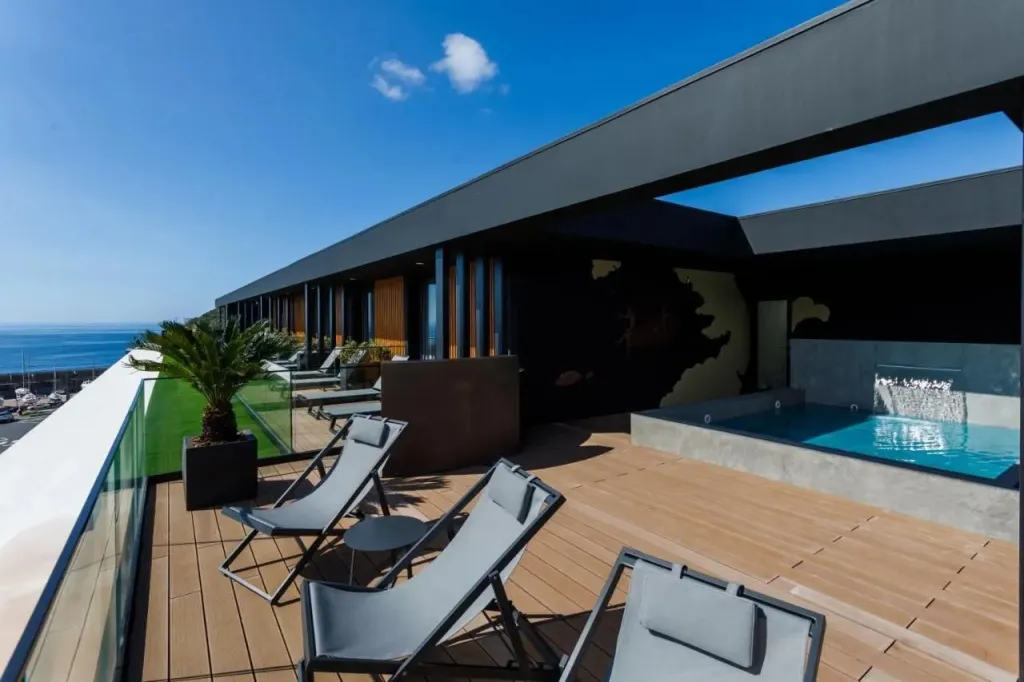 Terrasse aménagée avec transats et piscine à débordement.