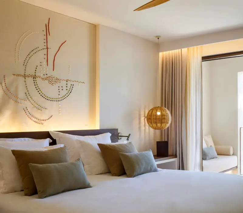 Une chambre lumineuse avec un grand lit recouvert de coussins.