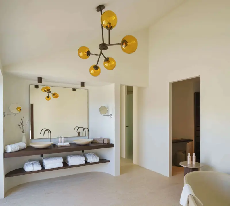 Une salle de bain lumineuse avec deux vasques et un grand miroir.