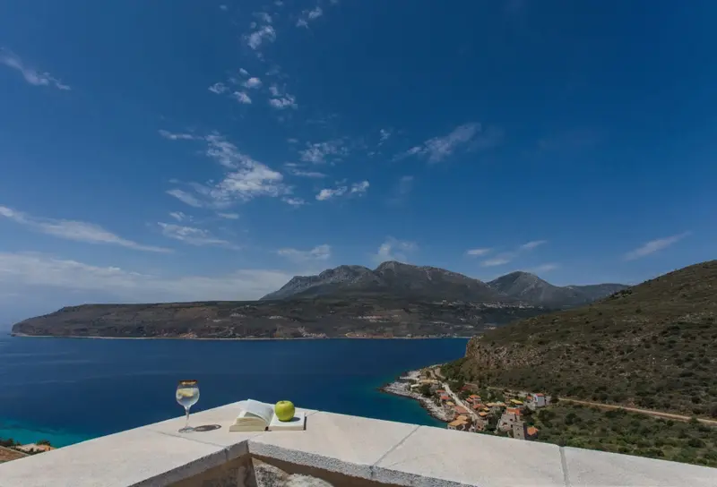 Vue panoramique sur la mer et les montagnes depuis une terrasse.