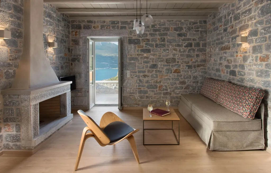 Un salon chaleureux avec une cheminée en pierre et une vue sur la mer.
