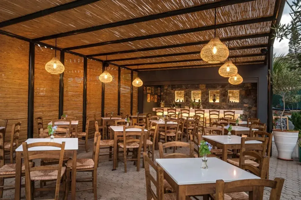 Une salle à manger extérieure avec des tables et des chaises en bois sous une pergola.