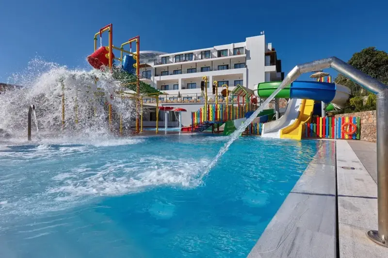 Une piscine avec des toboggans colorés et un bâtiment blanc en arrière-plan.