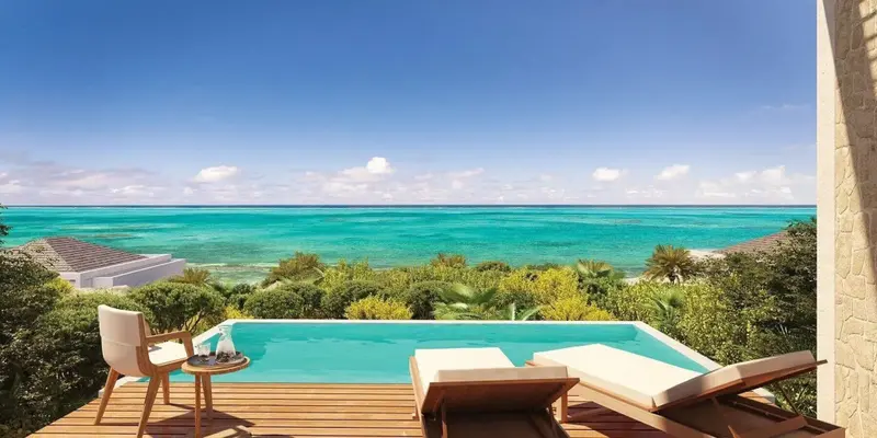 Terrasse avec piscine et vue sur la mer turquoise.