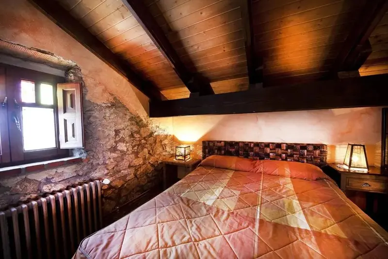 Une chambre à coucher chaleureuse avec un lit recouvert d'une courtepointe et une fenêtre en bois.