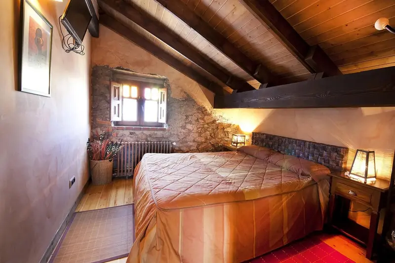 Une chambre mansardée avec un lit double et des meubles en bois.