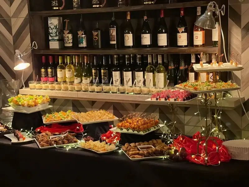 Un buffet garni de plats variés et de bouteilles de vin est présenté sur plusieurs niveaux.