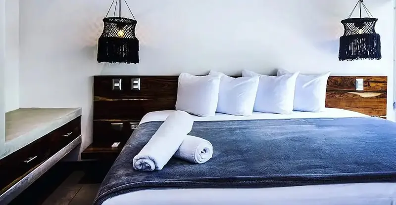 Un grand lit est dispose dans une chambre aux murs blancs.
