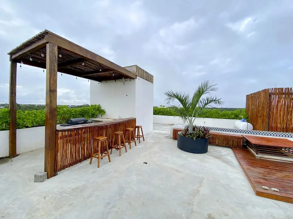 Un bar en plein air avec des tabourets en bois et une végétation luxuriante en arrière-plan.