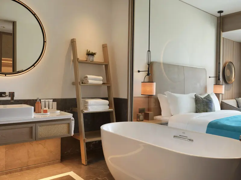 Une salle de bain lumineuse avec une baignoire et un lit en arrière-plan.