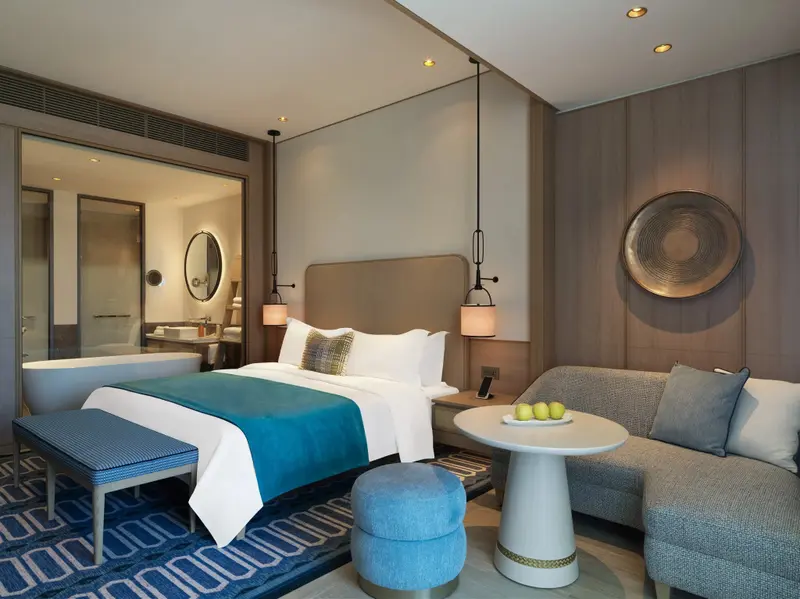 Une chambre lumineuse avec un grand lit et un coin salon.