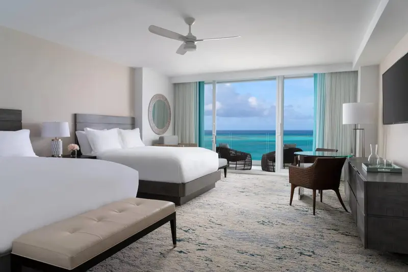Une chambre lumineuse avec deux lits et une vue sur la mer.