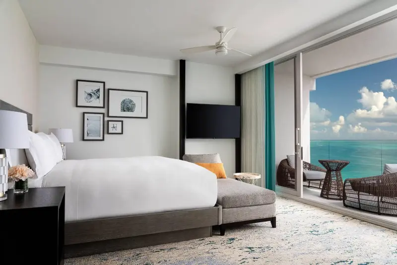 Une chambre lumineuse avec un grand lit donnant sur une vue mer.