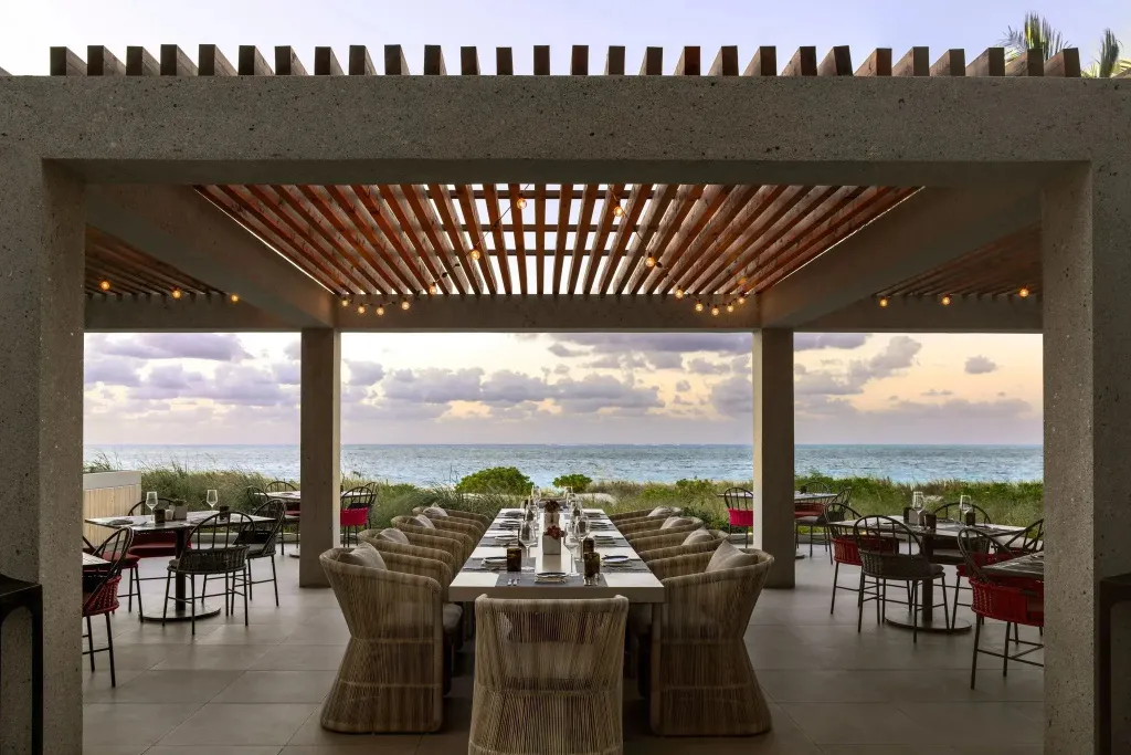 Une salle à manger extérieure offre une vue sur la mer au coucher du soleil.