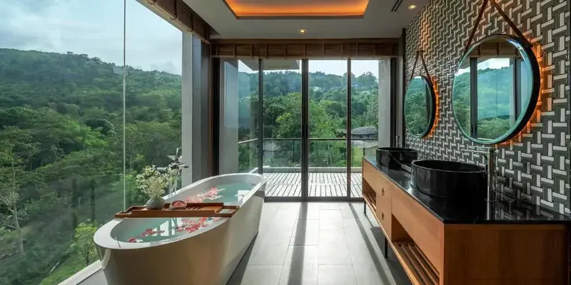 Une salle de bain lumineuse avec une baignoire et une vue sur la végétation.