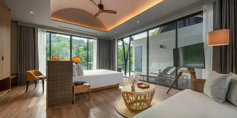 Une chambre lumineuse avec un lit et un espace salon donnant sur une terrasse.