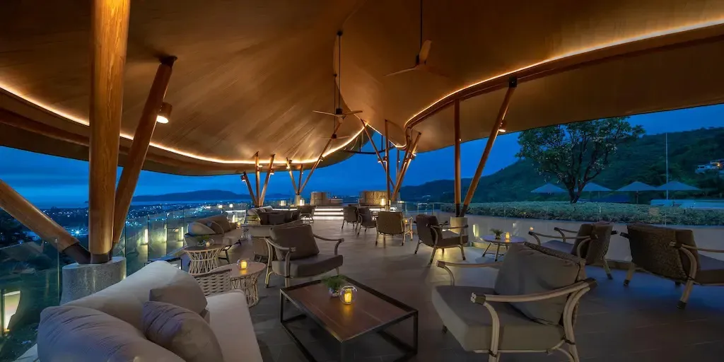 Espace de détente extérieur avec mobilier confortable et vue sur la ville illuminée.
