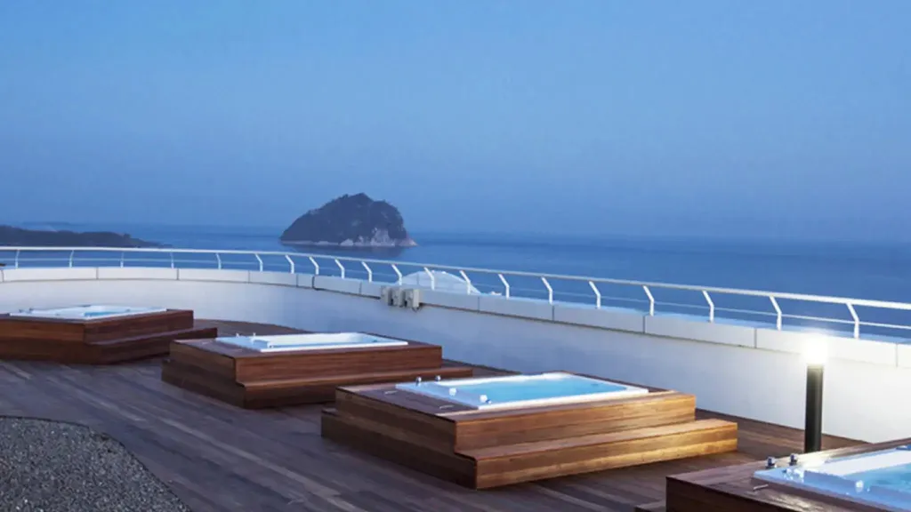 Terrasse avec plusieurs bains à remous face à la mer et à une île.