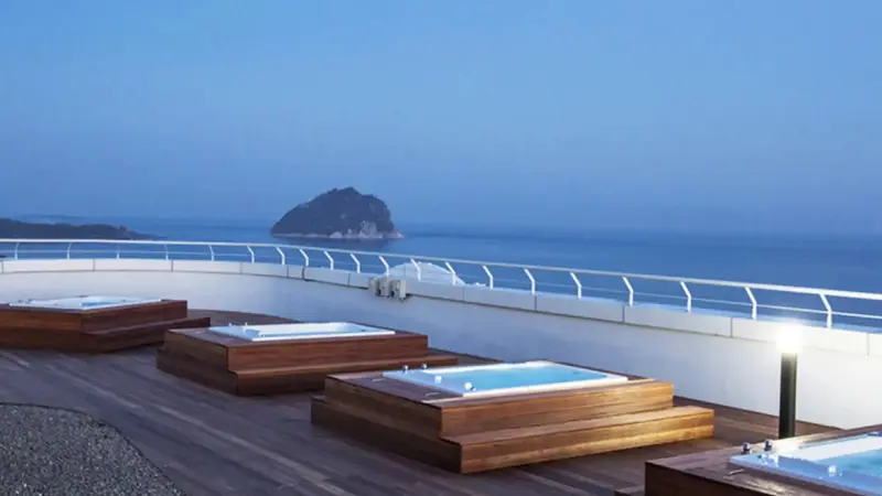 Terrasse avec plusieurs bains à remous face à la mer et à une île.