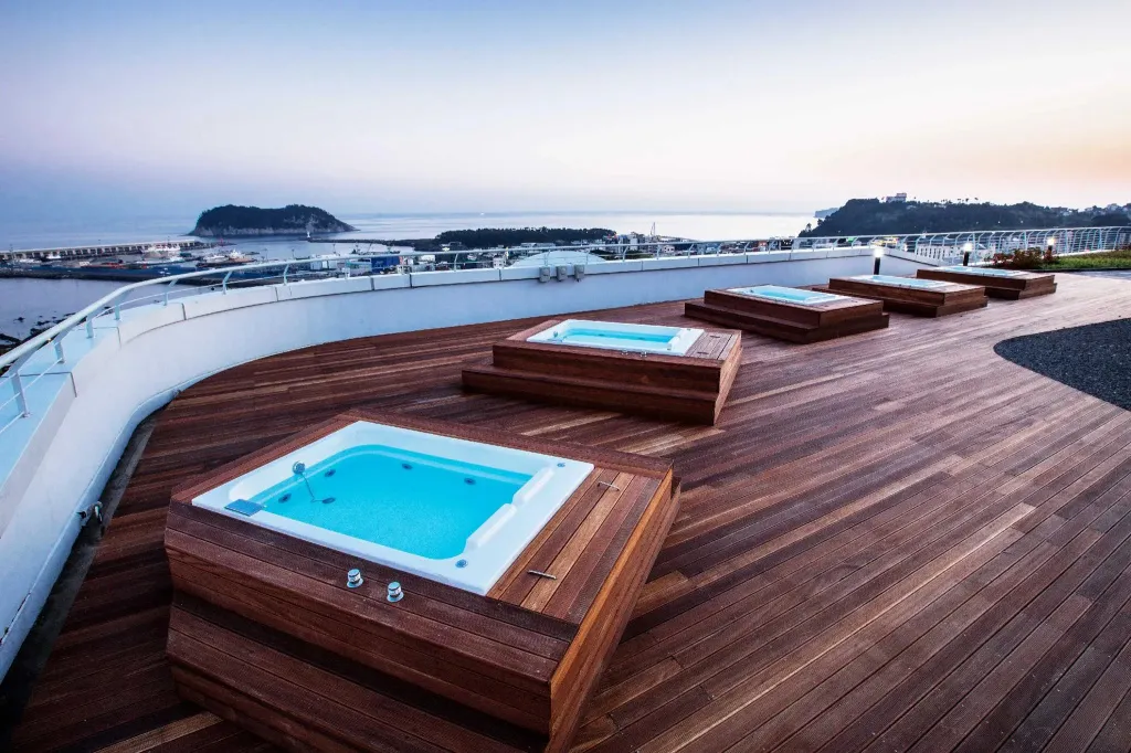 Terrasse avec plusieurs bains à remous en bois et vue sur la mer.