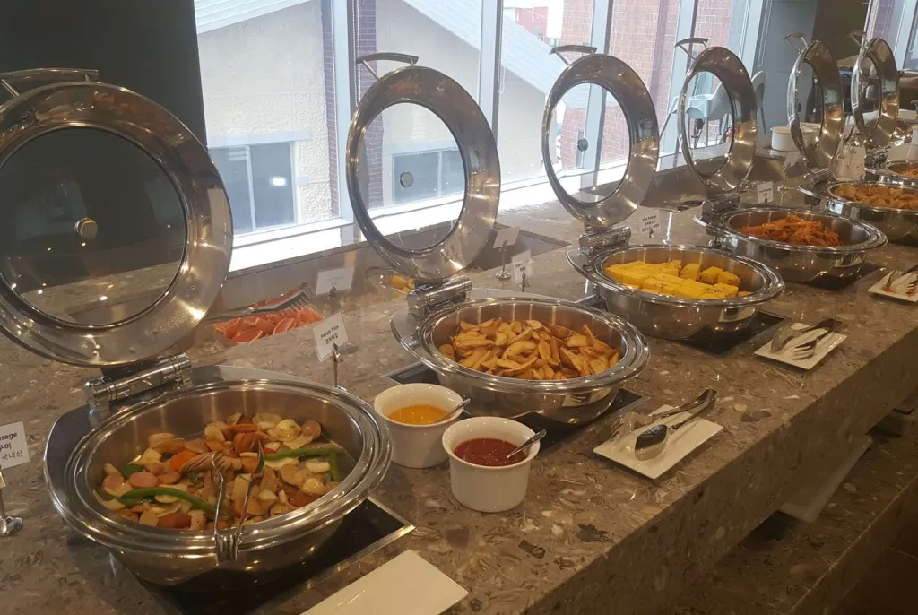 Un buffet propose une variété de plats chauds dans des récipients en métal.