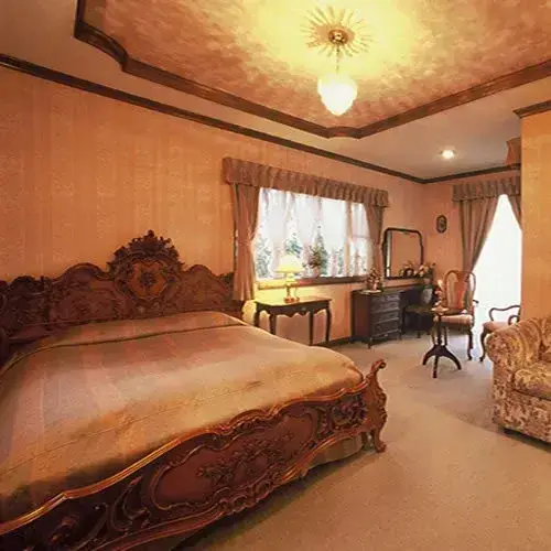Une chambre à coucher lumineuse avec un grand lit sculpté et un coin salon.