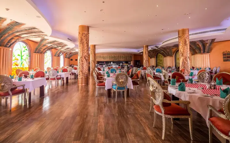 Une salle de restaurant lumineuse avec des tables dressées et des chaises décorées.