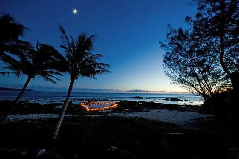 Ciel étoilé au-dessus d'une plage illuminée par des lumières disposées en forme de cœur.