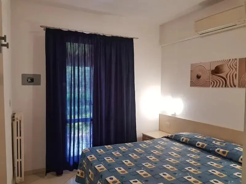 Une chambre lumineuse avec un grand lit et des rideaux bleus.