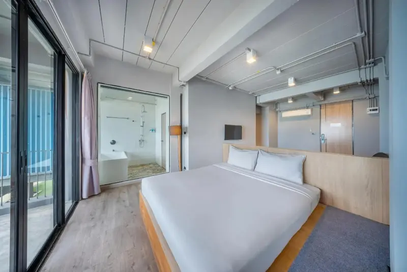 Une chambre lumineuse avec un grand lit et une salle de bain vitrée.