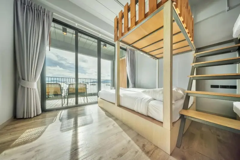 Une chambre lumineuse avec un lit superposé en bois et une vue sur la mer.