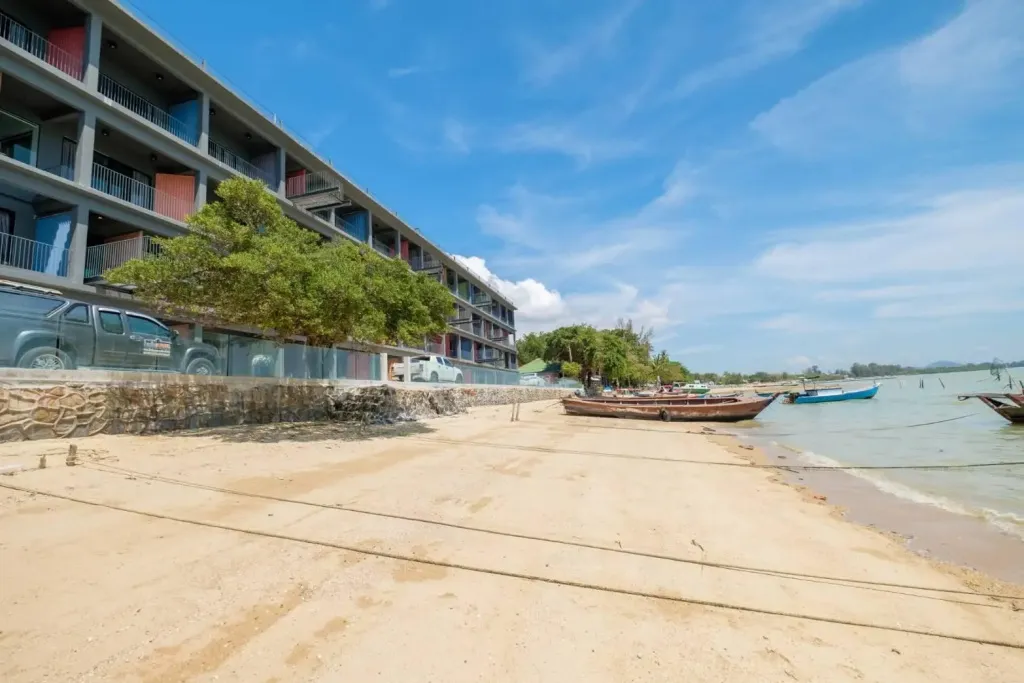 Bâtiment coloré le long d'une plage de sable fin avec des bateaux amarrés sur l'eau.