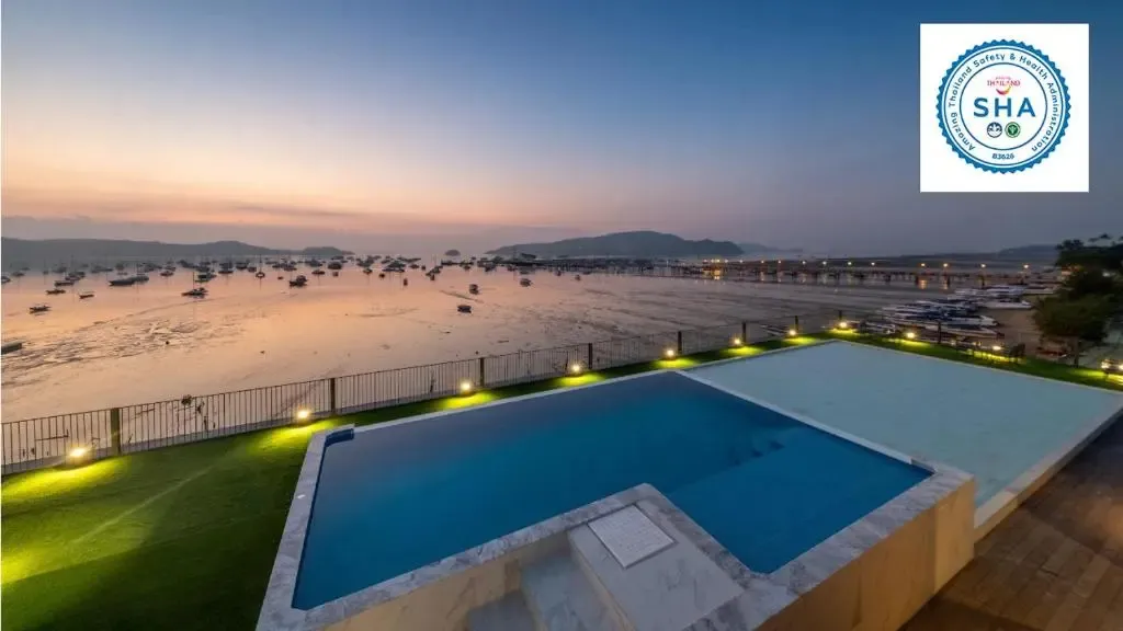 Une piscine à débordement offre une vue sur la mer et les bateaux amarrés au loin.