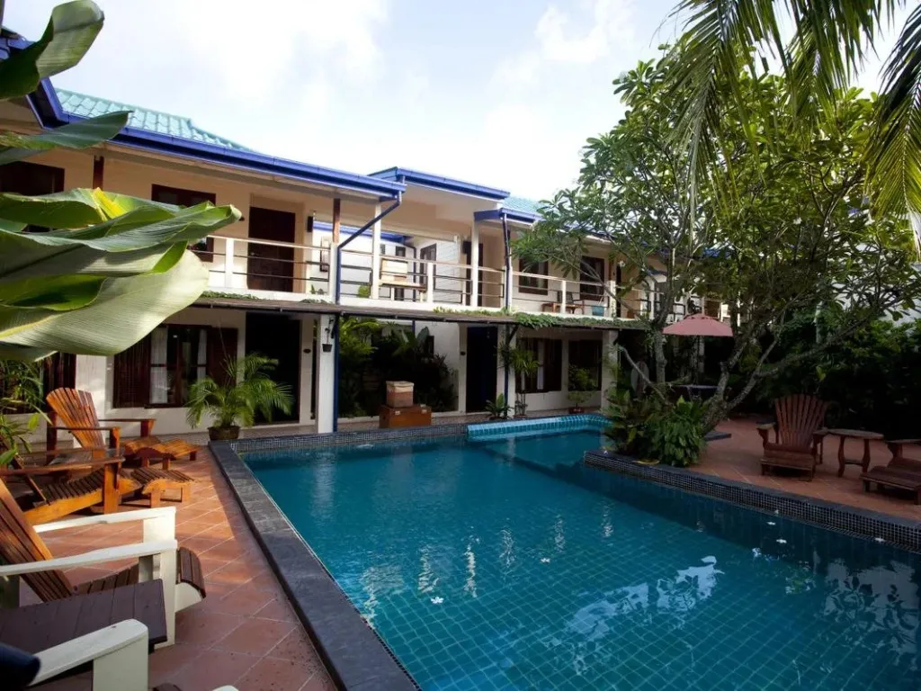 Une piscine turquoise bordée de chaises longues dans un jardin tropical.