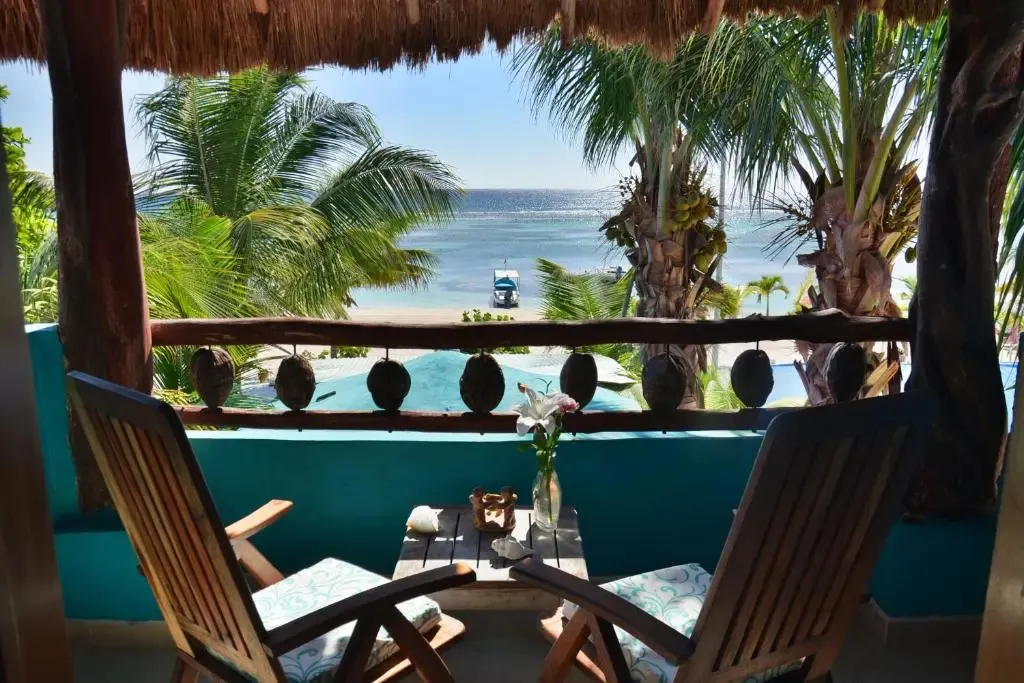 Deux fauteuils en bois invitent à la détente sur une terrasse ensoleillée avec vue sur la mer.