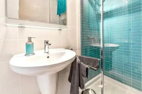 Une salle de bain claire avec douche et lavabo.