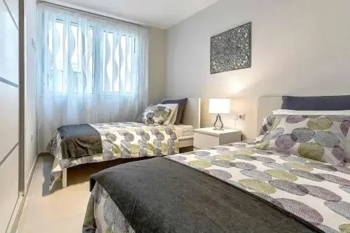 Une chambre lumineuse avec deux lits simples et une fenêtre drapée.