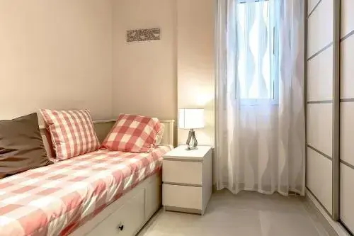 Une chambre lumineuse avec un lit simple et une table de chevet.