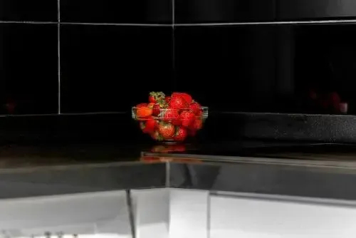Des fraises fraîches dans un saladier sur un comptoir sombre.