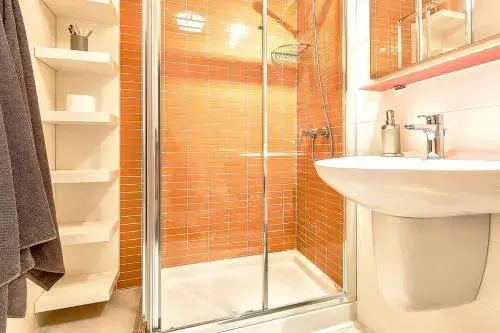 Une douche à l'italienne et un lavabo dans une salle de bain lumineuse.