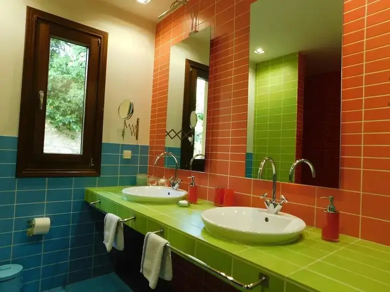 Une salle de bain colorée avec deux vasques et un grand miroir.