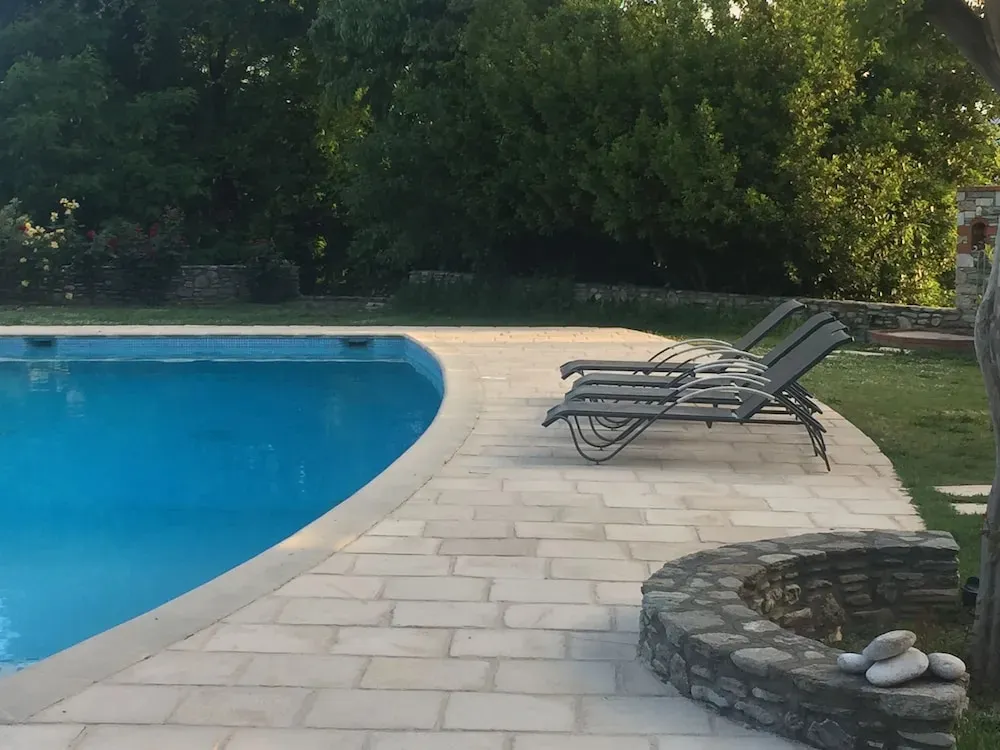 Transats alignés au bord d'une piscine rectangulaire en extérieur.